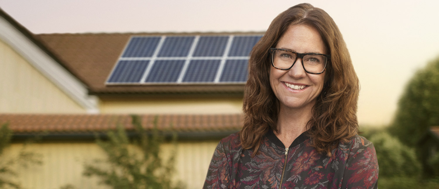 Kvinna står framför hus med solpaneler